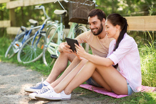 couple with tablet pc and bicycles at summer park - Foto, afbeelding