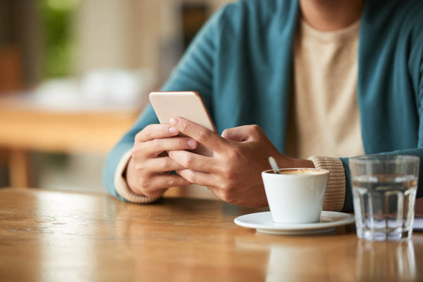 Man browsing phone at table with coffee cup - Photo, Image