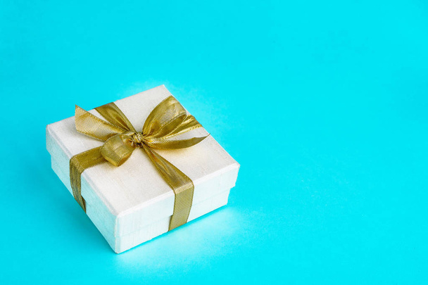 Gift or present box decorated with golden ribbon on blue background. Top view, copy space. Birthday, Mothers day, Wedding, Valentine Day concept. Holiday background. - Foto, immagini
