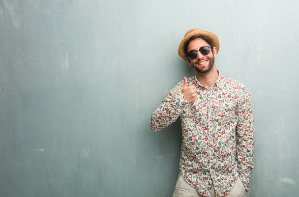 Mladý cestovatel muž nosí barevné tričko veselá a vzrušený, usmíval se a zvyšování její palec nahoru, pojetí úspěchu a schválení, ok gesto - Fotografie, Obrázek