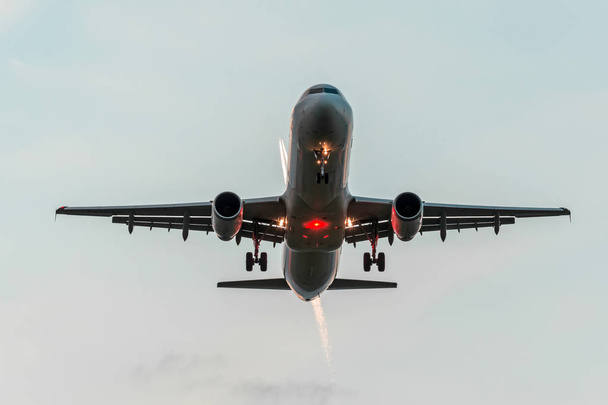 Zwei Flugzeuge am Himmel, eine bei der Annäherung vor der Landung auf dem Flughafen, die andere hoch mit einen Kondensstreifen in den Sonnenuntergang orangefarbenen Himmel - Foto, Bild