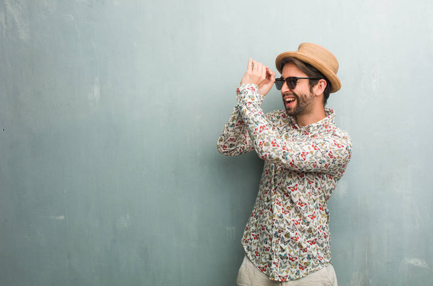 Jeune voyageur homme portant une chemise colorée regardant à travers un trou, se cachant et plissant
 - Photo, image
