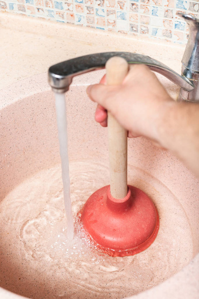man clears kitchen sink drain by rubber plunger - Photo, Image