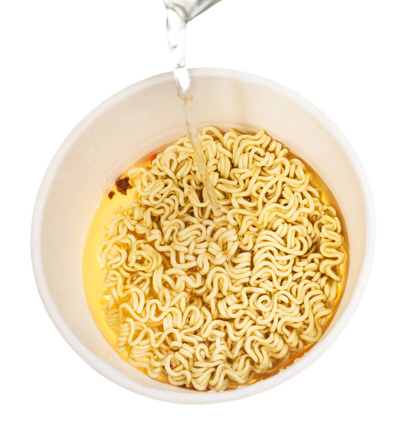 cooking instant noodles - water trickle flows in cup with dried instant noodles isolated on white background - Photo, Image