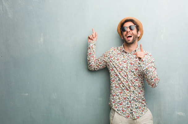 Νεαρός ταξιδιώτης άνθρωπος φορώντας ένα πολύχρωμο πουκάμισο ακούγοντας μουσική, χορό και έχοντας διασκέδαση, κινείται, φωνάζοντας και εκφράζοντας την ευτυχία, ελευθερία έννοια - Φωτογραφία, εικόνα