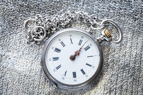 дві хвилини до дванадцятої години на старовинному кишеньковому годиннику на фоні срібної тканини
 - Фото, зображення