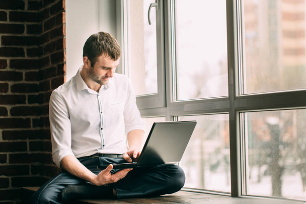 üzletember ül az ablak párkányára lótusz póz és szerkezet-ra a laptop, a szekrényben - Fotó, kép