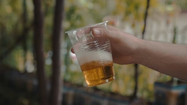 Holding ve yavaş şeffaf plastik bir kap Light bira ile sallayarak adam el  - Video, Çekim