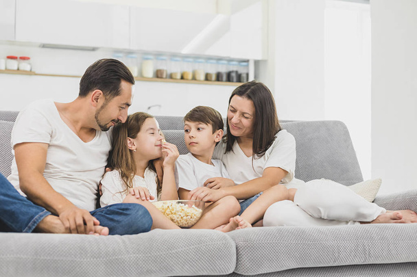Happy young family eating popcorn while watching tv in living room - Foto, Bild