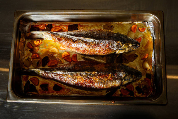 vista superior sobre pescado entero relleno a la parrilla con zanahorias, remolacha y trozos de cebolla servidos sobre metal tratar
 - Foto, imagen