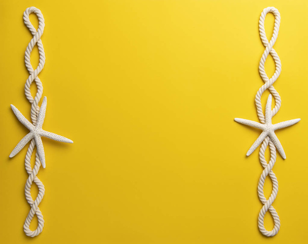 Concepto de hora de verano con estrellas de mar y cuerda sobre un fondo amarillo liso
 - Foto, Imagen