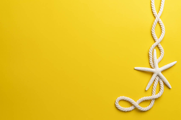 Summer time concept with starfish and rope on a plain yellow background - Photo, image