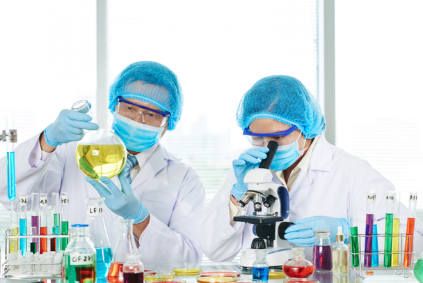 médicos cientistas que trabalham em laboratório e que utilizam microscópio
 - Foto, Imagem