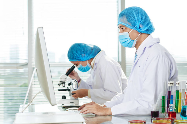 учёные-врачи, работающие с компьютером в лаборатории и с помощью микроскопа
 - Фото, изображение
