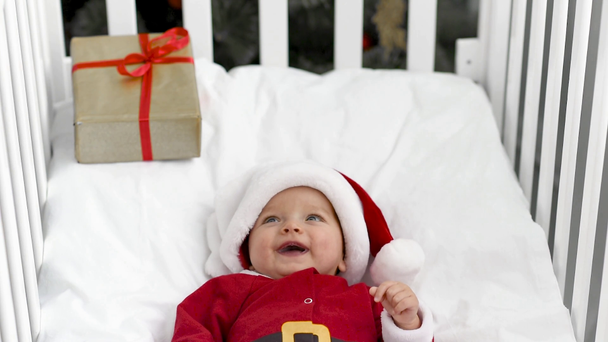 adorable baby in santa costume lying in crib with present box, christmas concept - Footage, Video