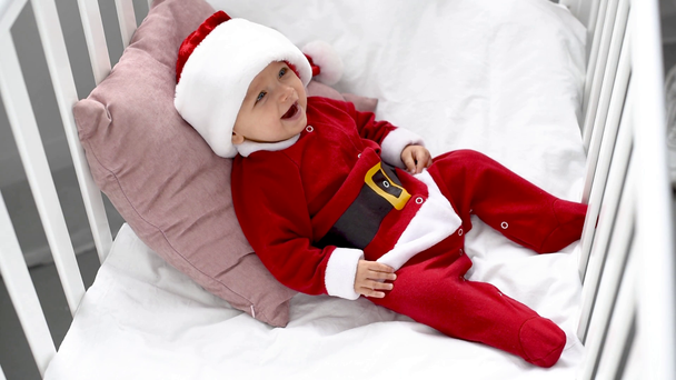 ihana hymyilevä vauva puvussa istuu pinnasängyssä kotona, joulukonsepti
 - Materiaali, video