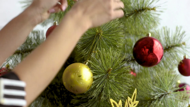 bijgesneden beeld van vrouw versieren kerstboom met ballen thuis - Video
