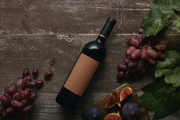 木製のテーブルに、空白のラベル、新鮮なブドウとイチジク ワイン ・ ボトルのトップ ビュー  - 写真・画像