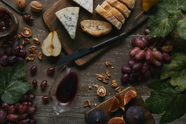vista dall'alto del vino rosso in vetro, frutta fresca e deliziosi snack sul tavolo di legno
 - Foto, immagini