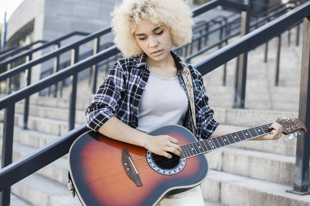Beautiful pensive girl practicing playing guitar outdoors - Foto, immagini