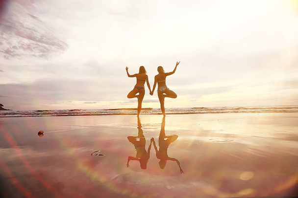 meditation and yoga on the beach. Two young women doing yoga on the sea shore - Foto, Imagem