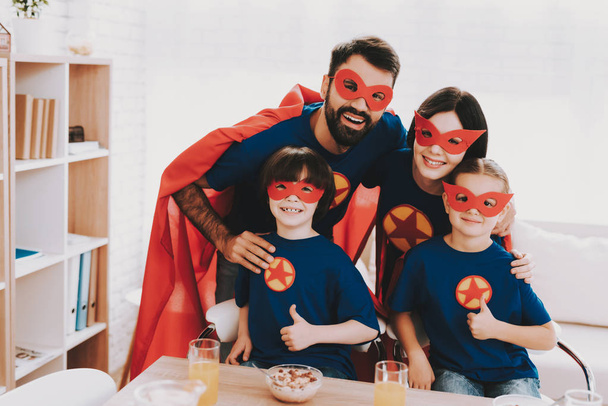 Young Family In Superhero Suits. Dinner Concept. Masks And Raincoats. Bright Room. Resting Together. Juice And Cereals. Get Ready. Healthy Lifestyle. Kids With A Parents. Thumbs Up. - Foto, immagini