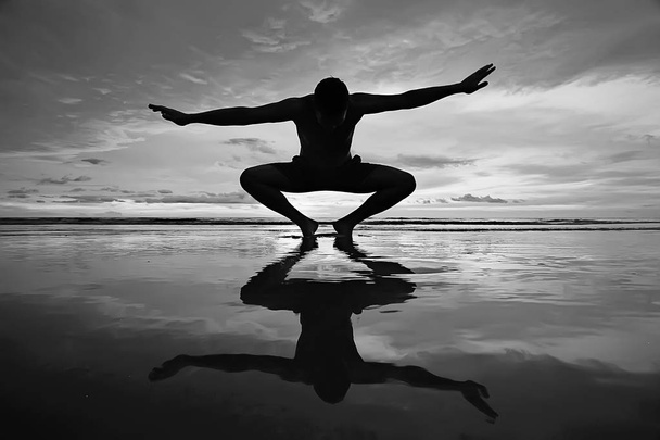 meditation and yoga on the beach. Young man doing yoga on the sea shore - 写真・画像