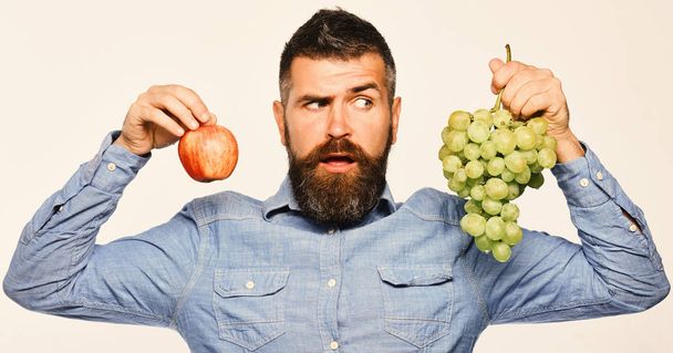 Man with beard holds bunch of green grapes and apple - Foto, Bild