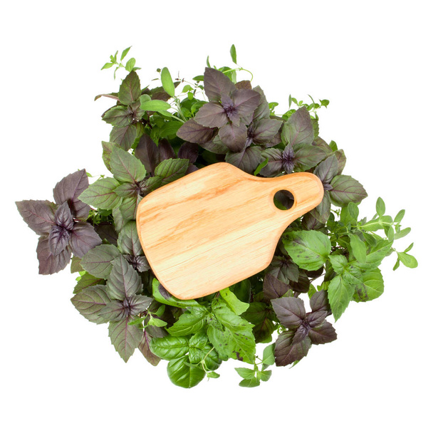 Tagliere in legno vuoto su varie foglie di basilico dolce
  - Foto, immagini