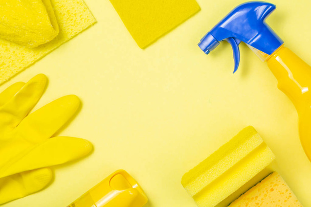 Cleaning supplies - yellow bottles, sprays sponge on bright pastel background - Foto, immagini