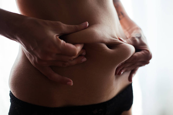 γυναίκα χέρι πιάνει την κοιλιά λίπος σώματος κοιλιά, διαβητική παράγοντας κινδύνου - Φωτογραφία, εικόνα