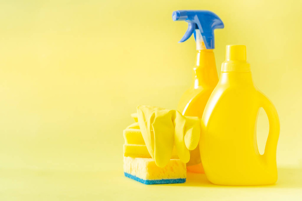 Cleaning supplies - yellow bottles, sprays sponge on bright pastel background - Foto, imagen