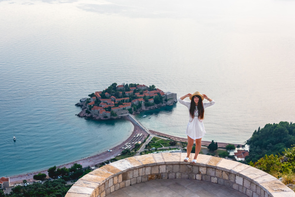 atractiva mujer de pie en el mirador cerca de la isla de San Esteban en el mar Adriático, Budva, Montenegro
 - Foto, Imagen