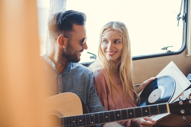 beautiful hippie couple resting inside trailer with acoustic guitar and  vinyl record  - Fotografie, Obrázek