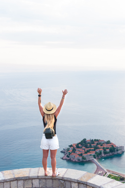vue de dos de la femme debout avec les mains levées et regardant l'île sainte Stephen dans la mer Adriatique, Budva, Monténégro
 - Photo, image