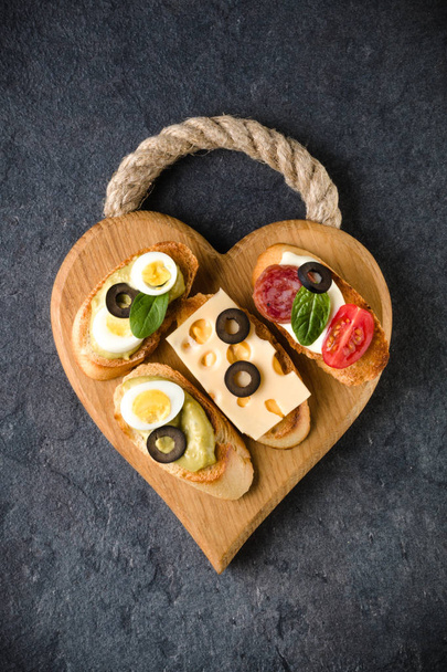 Open faced sandwich canape or crostini on a wooden serving board - 写真・画像