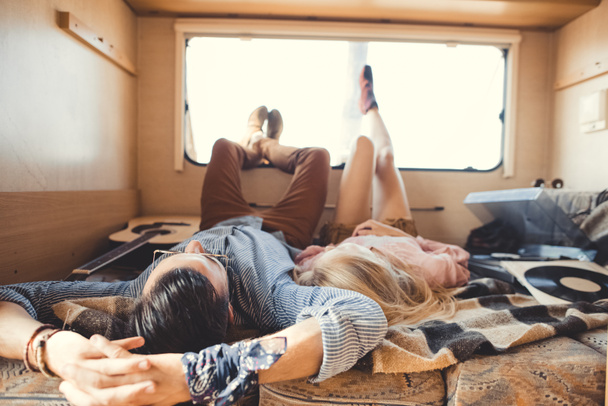 hippie couple lying inside campervan with acoustic guitar and vinyl player - Foto, Bild