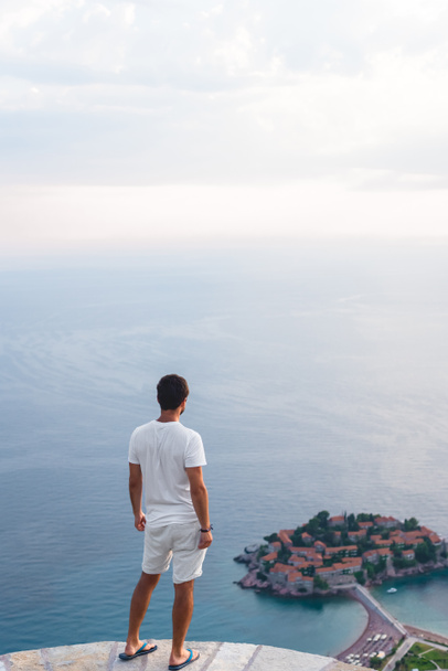 vue arrière de l'homme regardant l'île de Sveti Stefan avec hôtel station balnéaire dans la mer Adriatique, Budva, Monténégro
 - Photo, image