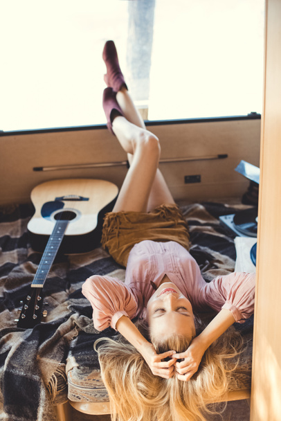 Dziewczyna hipis relaksujący wewnątrz przyczepy z akustyczna gitara i vinyl player  - Zdjęcie, obraz