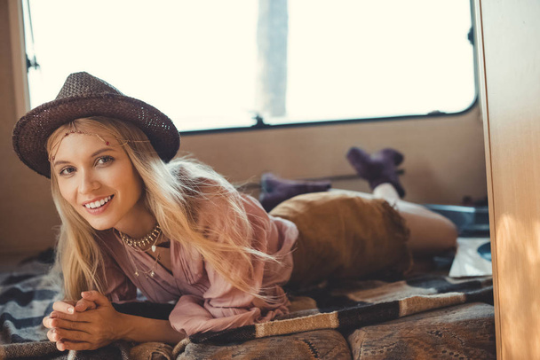 smiling hippie girl lying inside camper van - Photo, Image