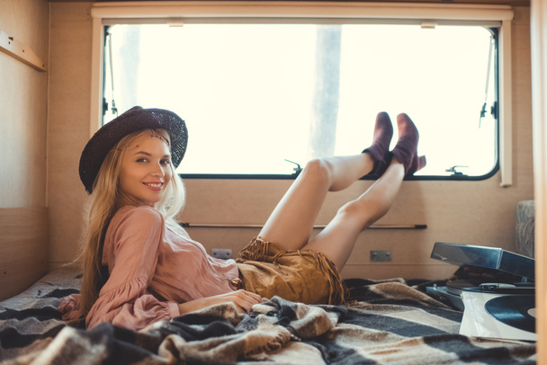 attractive hippie girl lying inside camper van with vinyl player and records - Fotó, kép