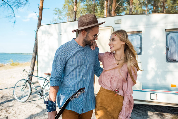 young hippie couple hugging and walking near trailer - Photo, Image