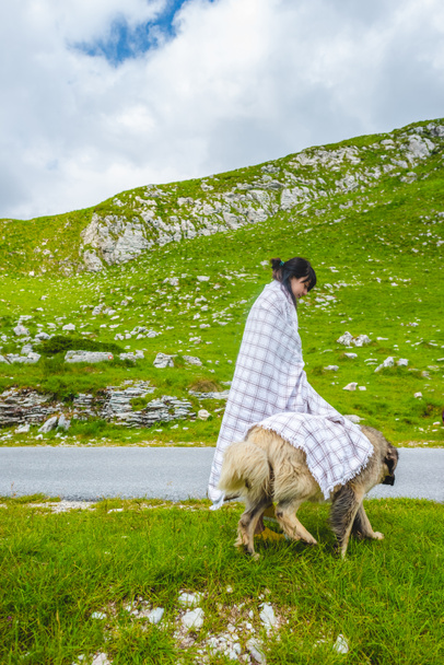 mooie vrouw in deken bedekking pluizige hond op vallei in Durmitor-massief, Montenegro - Foto, afbeelding