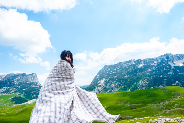 ドゥルミトル山地、モンテネグロの山近くの渓谷の上を歩く毛布で美しい女性 - 写真・画像