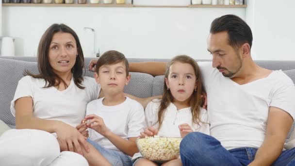 自宅でリラックスした 2 人の子供と幸せな家庭子供兄と妹映画を見ていて、両親とポップコーン - 映像、動画