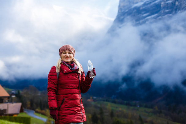 Sırt çantalı genç bir kadın dağın tepesinde duruyor.  - Fotoğraf, Görsel
