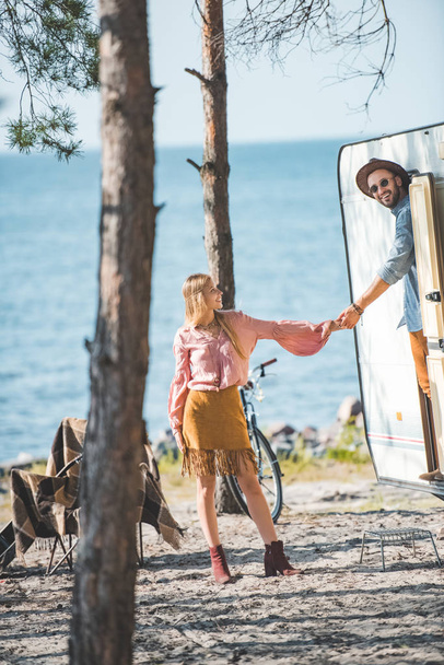 hippie pareja cogido de la mano y va a dar un paseo en campervan cerca del mar
 - Foto, imagen