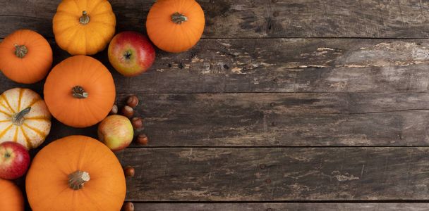 Autumn harvest still life with pumpkins , apples , hazelnuts on wooden background , top view - Фото, изображение
