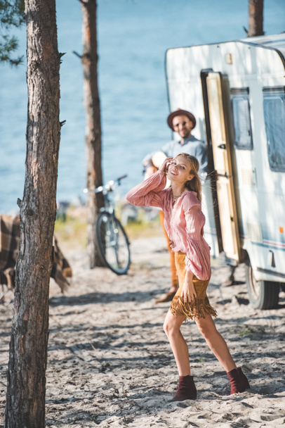 attractive happy girl dancing while man playing guitar near campervan - Photo, Image