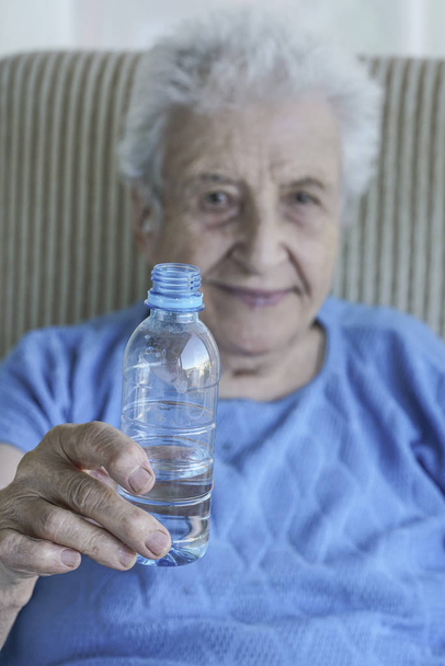Μια όμορφη γυναίκα ανώτερος κρατώντας ένα μπουκάλι του πόσιμου νερού - Φωτογραφία, εικόνα